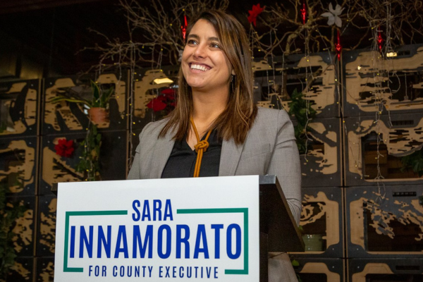 Sara Innamorato at a podium with a campaign sign for County Executive